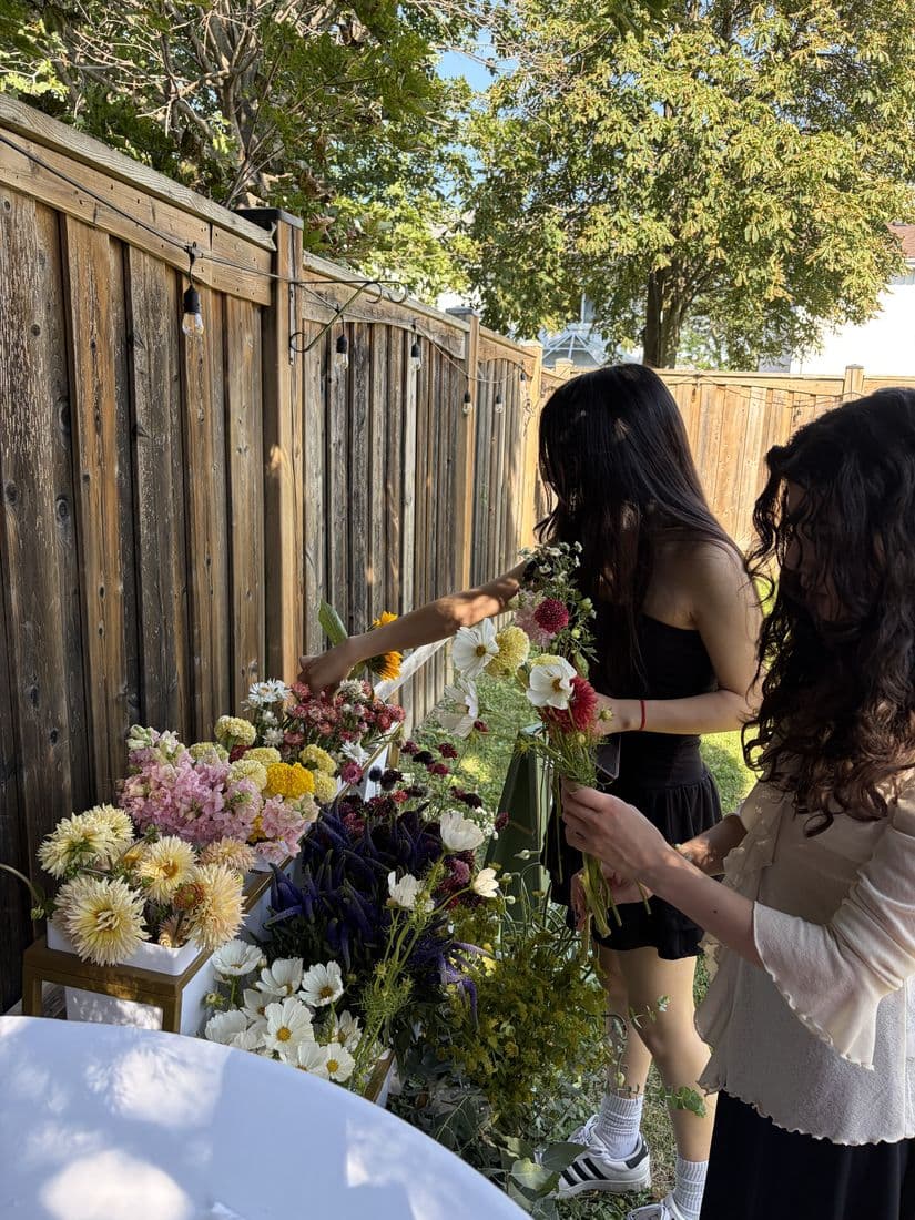 Two guests picking stems from the Bloom Bar at a backyard party