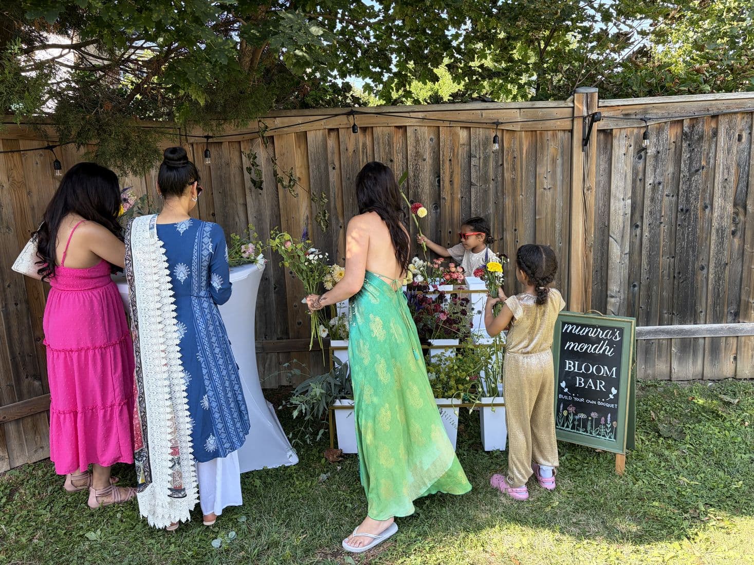 Guests of all ages gathered around the Bloom Bar at a backyard celebration