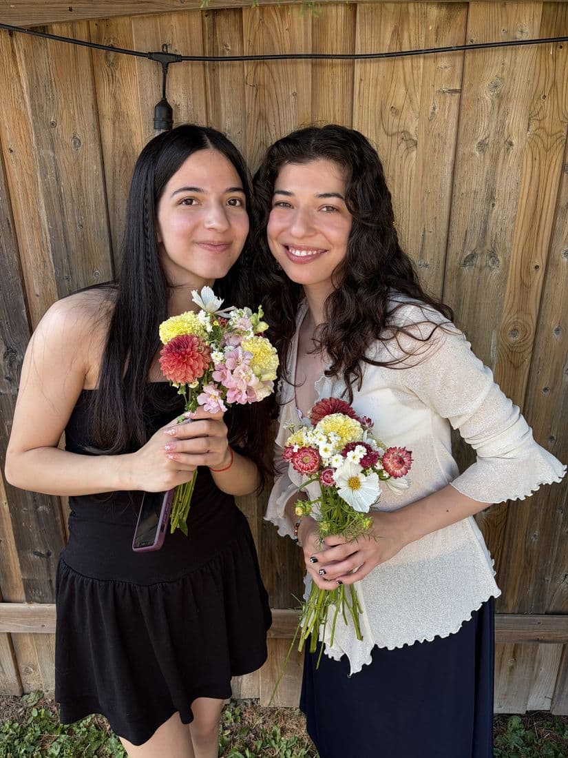 Two friends smiling with the hand-tied posies they just made